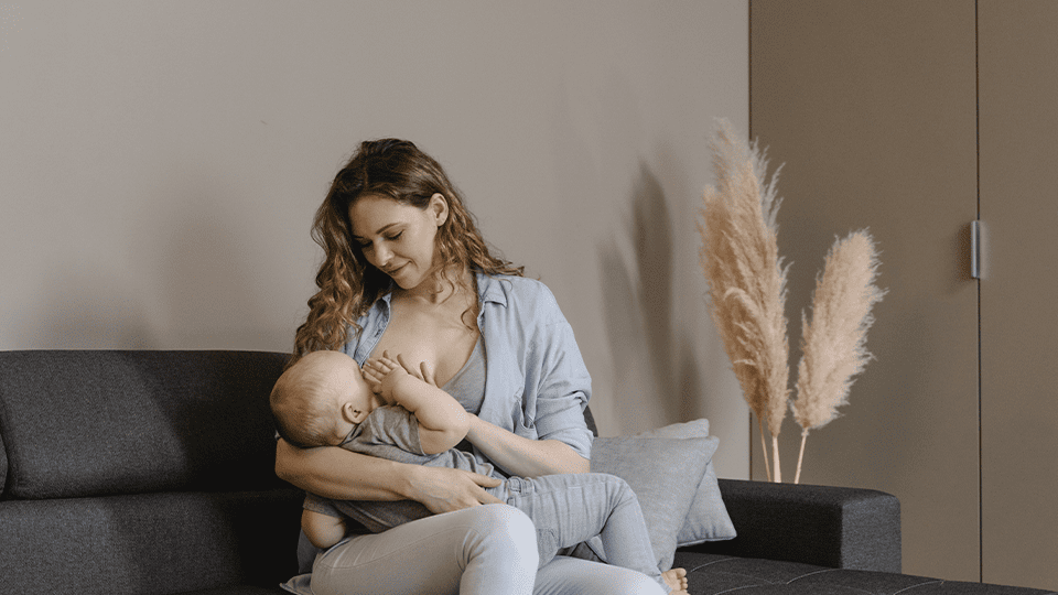 Женщина сидит на полу, обняв колени, и выглядит задумчивой